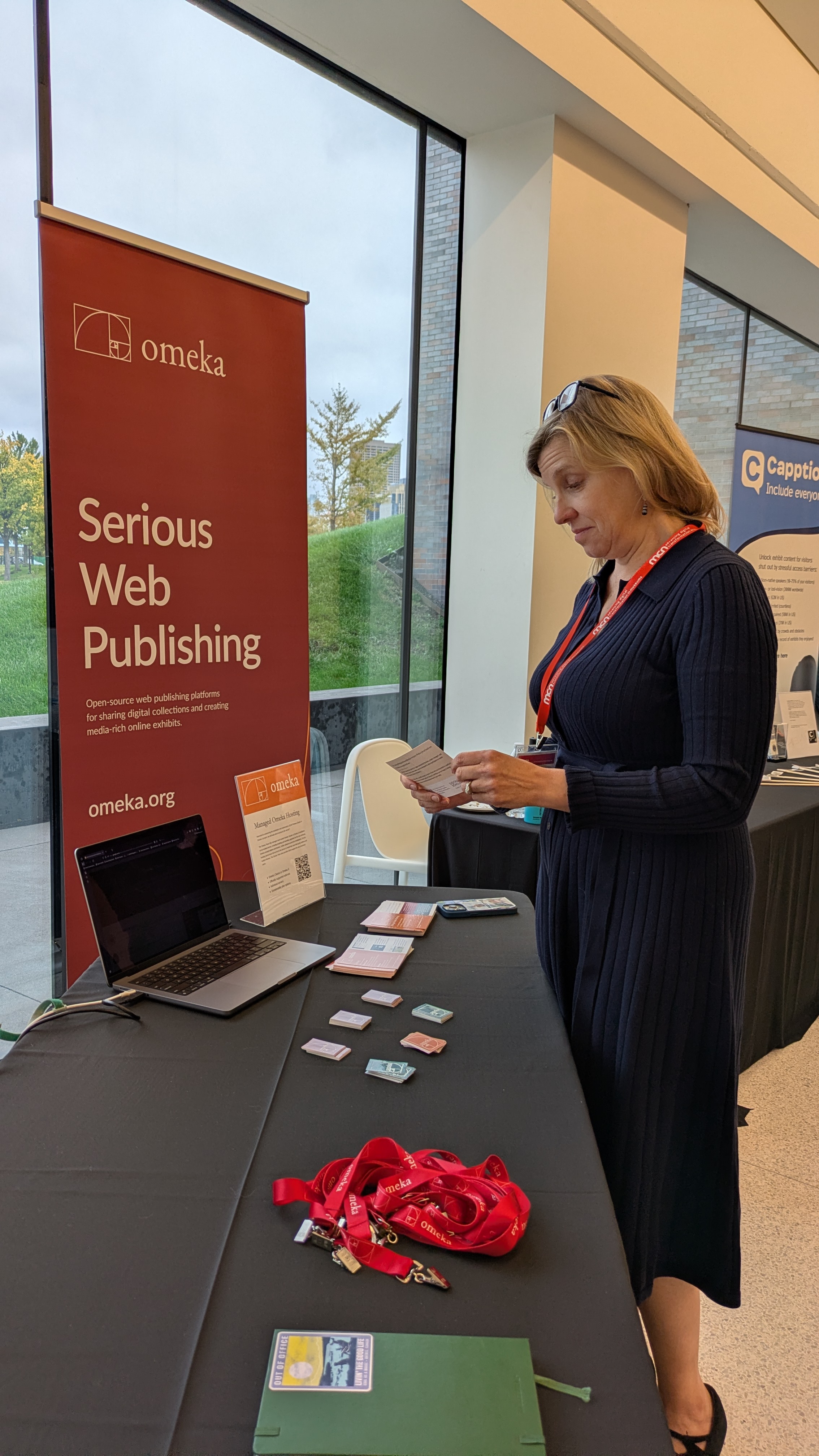 A blonde woman examines the Omeka table at MCN